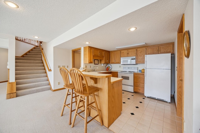 1181 12th Ave NW, New Brighton, MN 55112 - kitchen with white appliances, a textured ceiling, a peninsula, a breakfast bar area, and light countertops