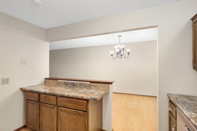 5661 Windmill Dr, White Bear Twp, MN 55110 - kitchen featuring a peninsula, light wood finished floors, a chandelier, and brown cabinets