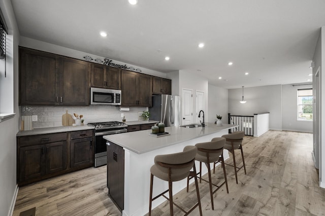 8698 London Cir NE Unit C, Blaine, MN 55449 - kitchen featuring stainless steel appliances, light wood-type flooring, an island with sink, a kitchen breakfast bar, and dark brown cabinetry
