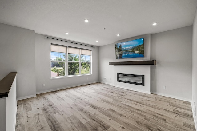 8698 London Cir NE Unit C, Blaine, MN 55449 - unfurnished living room with wood finished floors, a glass covered fireplace, and recessed lighting
