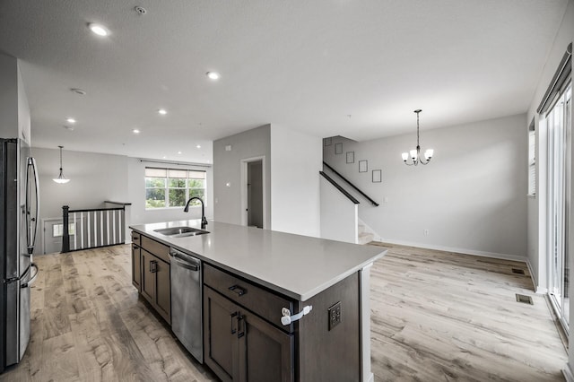 8698 London Cir NE Unit C, Blaine, MN 55449 - kitchen with stainless steel appliances, light wood finished floors, dark brown cabinets, a kitchen island with sink, and a chandelier