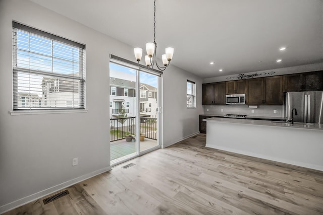 8698 London Cir NE Unit C, Blaine, MN 55449 - kitchen with stainless steel appliances, a chandelier, dark brown cabinetry, light wood-style floors, and hanging light fixtures
