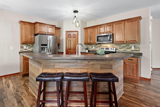 11608 21st St NE, Saint Michael, MN 55376 - kitchen featuring appliances with stainless steel finishes, dark countertops, brown cabinets, backsplash, and a breakfast bar area