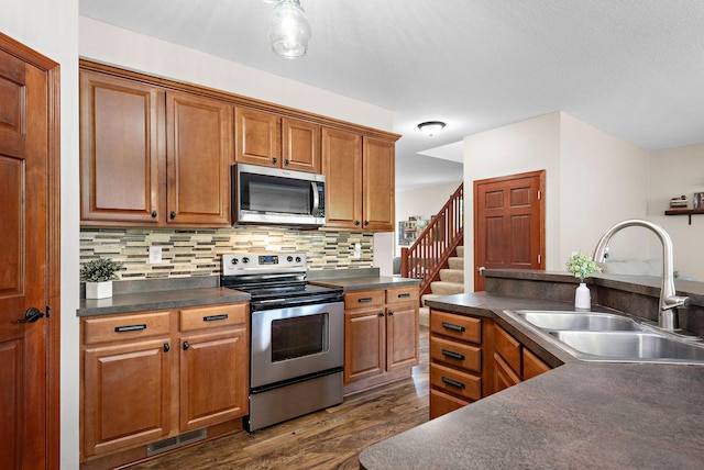11608 21st St NE, Saint Michael, MN 55376 - kitchen with appliances with stainless steel finishes, dark countertops, dark wood finished floors, brown cabinets, and decorative backsplash