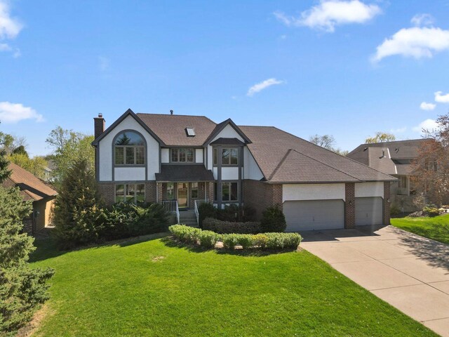 8700 Kilbirnie Ter, Brooklyn Park, MN 55443 - english style home with brick siding, an attached garage, concrete driveway, a front yard, and a chimney