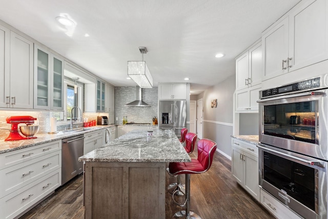 8700 Kilbirnie Ter, Brooklyn Park, MN 55443 - kitchen featuring appliances with stainless steel finishes, decorative backsplash, glass insert cabinets, a breakfast bar, and a center island