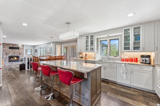 8700 Kilbirnie Ter, Brooklyn Park, MN 55443 - kitchen with recessed lighting, dark wood finished floors, a breakfast bar, a fireplace, and white cabinets