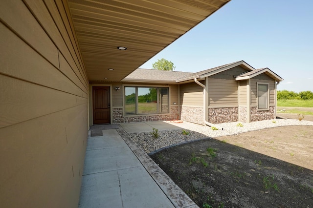 1722 41st Ave NE, Dovre Twp, MN 56201 - doorway to property featuring stone siding, a patio, and roof with shingles