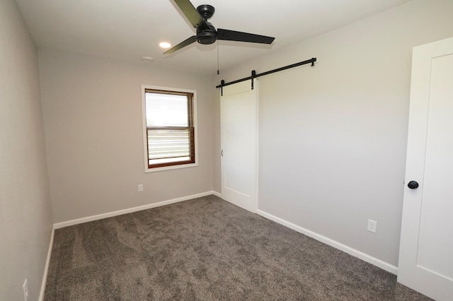 1722 41st Ave NE, Dovre Twp, MN 56201 - unfurnished room with a barn door, a ceiling fan, and dark colored carpet