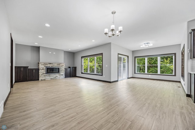 3702 Houkom Dr E, Fargo, ND 58078 - unfurnished living room featuring a chandelier, light wood-type flooring, a stone fireplace, and recessed lighting