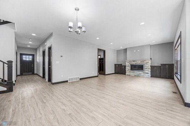 3702 Houkom Dr E, Fargo, ND 58078 - unfurnished living room with a chandelier, light wood finished floors, stairs, a stone fireplace, and recessed lighting