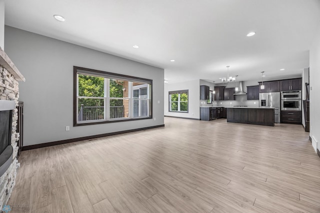 3702 Houkom Dr E, Fargo, ND 58078 - unfurnished living room with a chandelier, light wood-type flooring, a fireplace, and recessed lighting