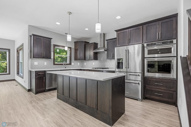 3702 Houkom Dr E, Fargo, ND 58078 - kitchen with stainless steel appliances, wall chimney exhaust hood, dark brown cabinetry, backsplash, and light countertops
