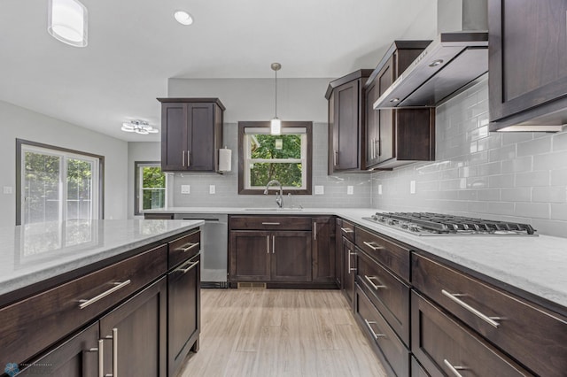 3702 Houkom Dr E, Fargo, ND 58078 - kitchen with appliances with stainless steel finishes, wall chimney range hood, tasteful backsplash, dark brown cabinetry, and hanging light fixtures