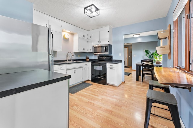 19172 Front Blvd NE, East Bethel, MN 55092 - kitchen featuring stainless steel appliances, dark countertops, light wood-style flooring, white cabinetry, and a textured ceiling