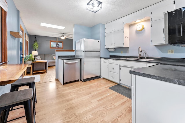 19172 Front Blvd NE, East Bethel, MN 55092 - kitchen featuring freestanding refrigerator, light wood finished floors, dishwasher, dark countertops, and white cabinetry