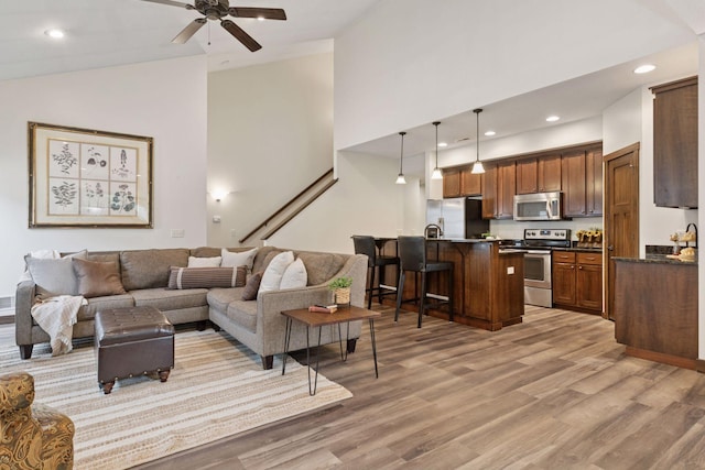 98 Tribute Ave, Hudson, WI 54016 - living room featuring high vaulted ceiling, light wood finished floors, ceiling fan, recessed lighting, and stairway