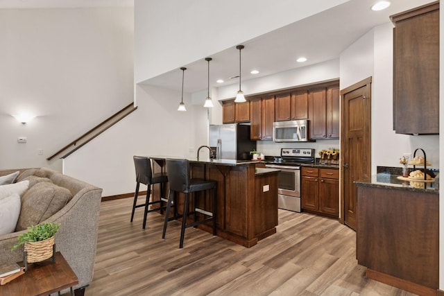 98 Tribute Ave, Hudson, WI 54016 - kitchen with appliances with stainless steel finishes, a breakfast bar, light wood-style floors, recessed lighting, and open floor plan