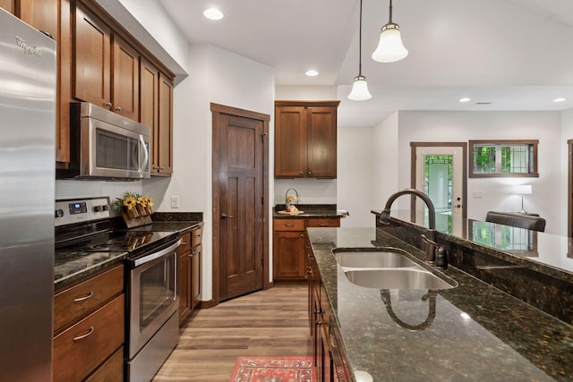 98 Tribute Ave, Hudson, WI 54016 - kitchen featuring appliances with stainless steel finishes, light wood-type flooring, pendant lighting, dark stone countertops, and recessed lighting