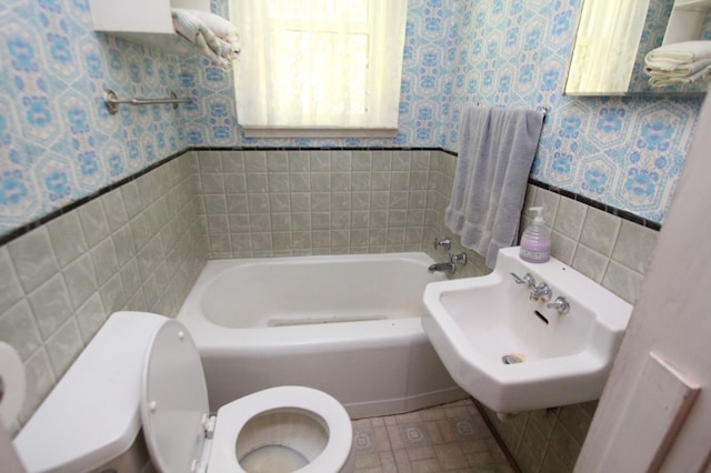 24195 Center St E, Mayfield Twp, MN 56701 - bathroom with tile walls, a bath, a wainscoted wall, and wallpapered walls