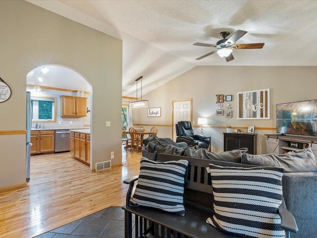 4669 Brentwood Rd, Baxter, MN 56425 - living area with lofted ceiling, healthy amount of natural light, ceiling fan, light wood finished floors, and a textured ceiling