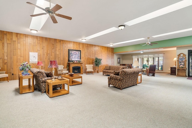 1200 18th Ave NW Unit 132, Austin, MN 55912 - carpeted living room featuring wooden walls, a ceiling fan, a skylight, and a lit fireplace