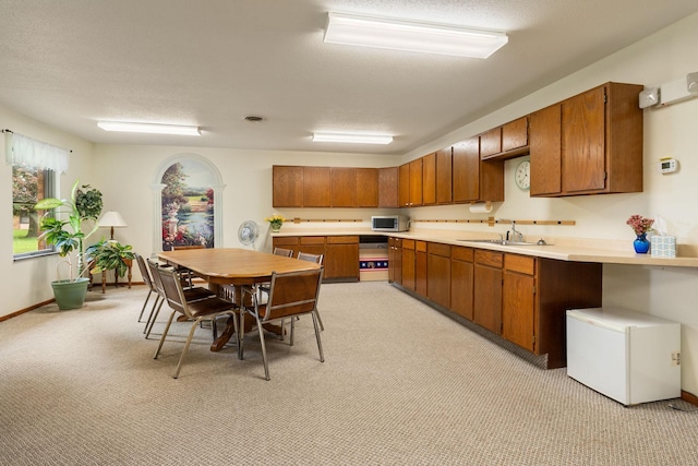 1200 18th Ave NW Unit 132, Austin, MN 55912 - kitchen featuring stainless steel microwave, light countertops, brown cabinets, and light colored carpet