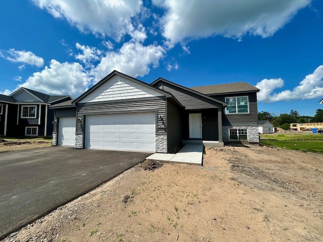6706 376th St, North Branch, MN 55056 - split level home with an attached garage, asphalt driveway, and stone siding