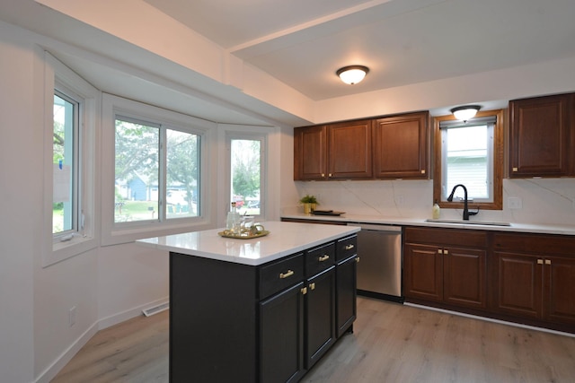 10419 Goldenrod St NW, Coon Rapids, MN 55448 - kitchen with dishwasher, light countertops, light wood-style flooring, backsplash, and a center island