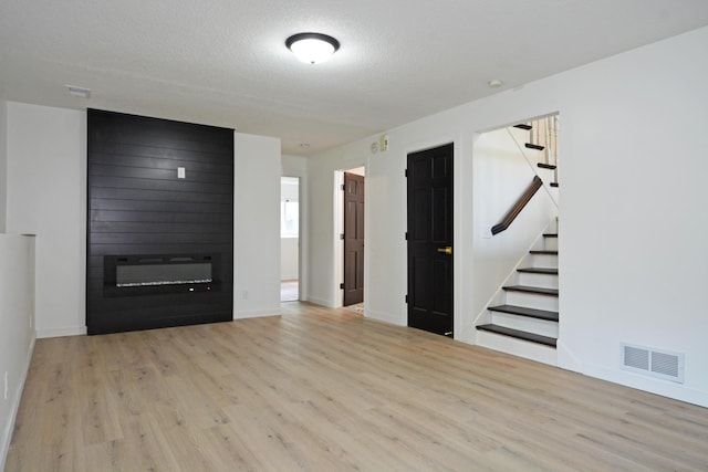 10419 Goldenrod St NW, Coon Rapids, MN 55448 - unfurnished living room featuring wood finished floors, stairway, a large fireplace, and a textured ceiling