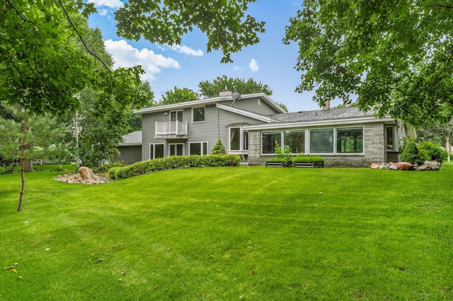 213 2nd St N, Cold Spring, MN 56320 - back of property featuring a balcony, a lawn, a chimney, and stone siding