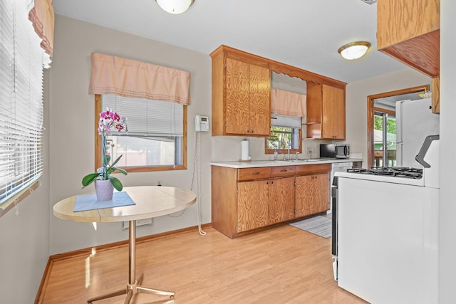 5913 Zenith Ave N, Brooklyn Center, MN 55429 - kitchen with light countertops, white appliances, light wood finished floors, and brown cabinets
