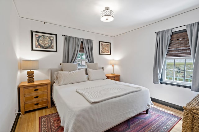 704 58th St, Minneapolis, MN 55417 - bedroom featuring multiple windows, light wood-style flooring, and a baseboard radiator