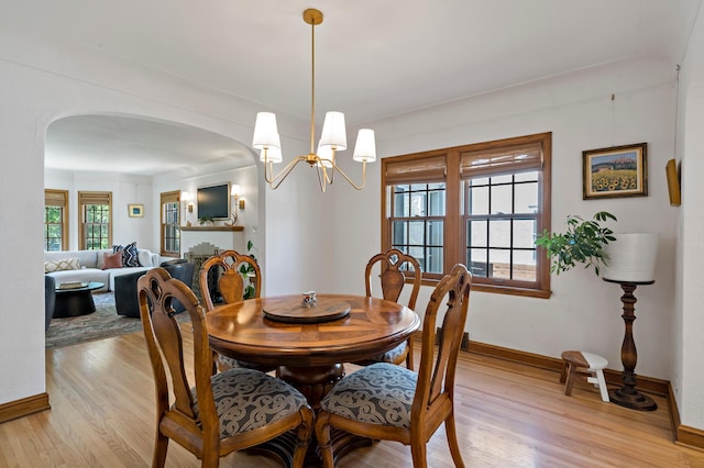 704 58th St, Minneapolis, MN 55417 - dining space with arched walkways, light wood-type flooring, and a chandelier