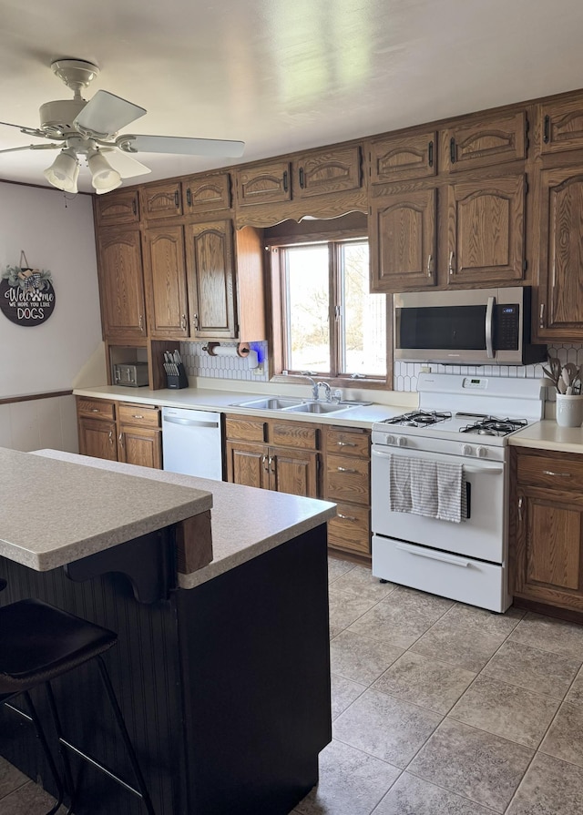 74194 415th St, South Branch Twp, MN 56081 - kitchen with white appliances, light countertops, ceiling fan, backsplash, and wainscoting