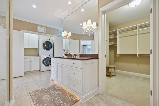 875 Lake St N Unit 318, Wayzata, MN 55391 - bathroom featuring stacked washing machine and dryer, a chandelier, vanity, ornamental molding, and a walk in closet