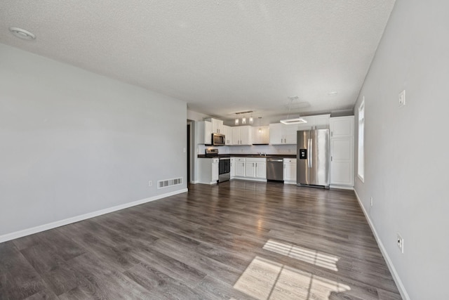 12651 8th Ave S, Zimmerman, MN 55398 - unfurnished living room with a textured ceiling and dark wood-style flooring
