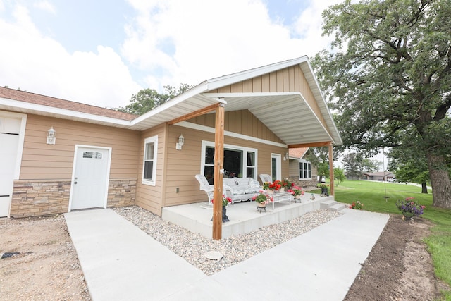 915 Darling Dr NW, Alexandria, MN 56308 - view of front of house featuring board and batten siding, a patio, a front yard, and stone siding