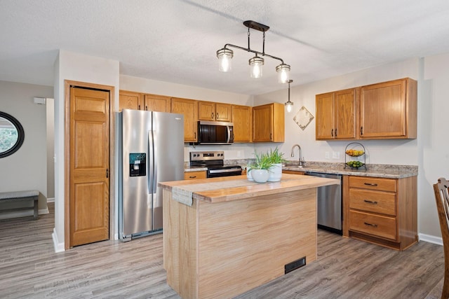 1807 Lachman Ave NE, Saint Michael, MN 55376 - kitchen featuring appliances with stainless steel finishes, light wood finished floors, a kitchen island, hanging light fixtures, and brown cabinets
