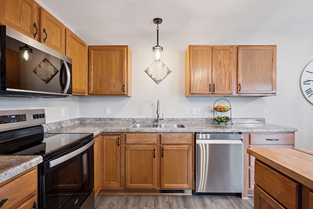 1807 Lachman Ave NE, Saint Michael, MN 55376 - kitchen featuring appliances with stainless steel finishes, light wood finished floors, a textured ceiling, hanging light fixtures, and brown cabinets