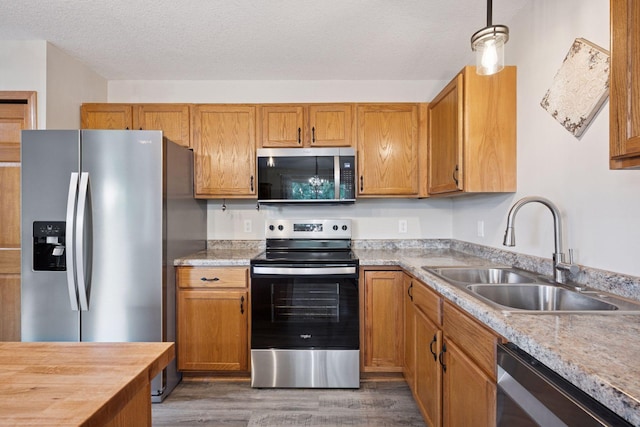 1807 Lachman Ave NE, Saint Michael, MN 55376 - kitchen with appliances with stainless steel finishes, wood finished floors, a textured ceiling, brown cabinets, and hanging light fixtures