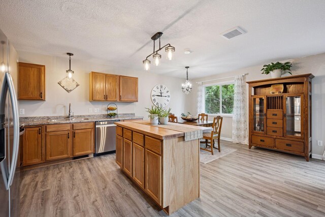 1807 Lachman Ave NE, Saint Michael, MN 55376 - kitchen with stainless steel appliances, light wood-style floors, butcher block counters, a textured ceiling, and brown cabinetry