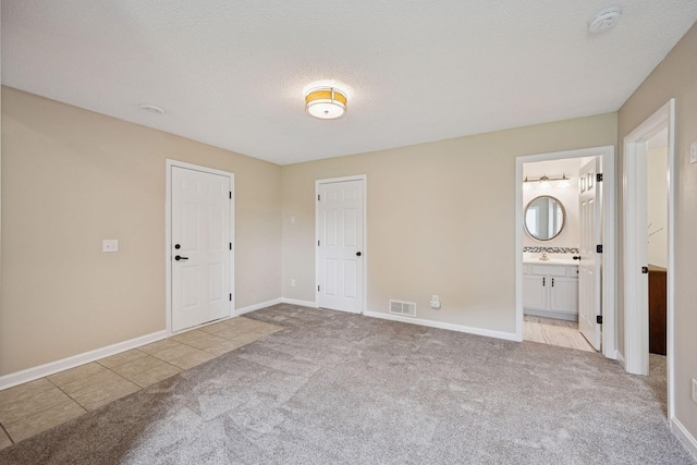 1807 Lachman Ave NE, Saint Michael, MN 55376 - unfurnished bedroom featuring carpet floors, ensuite bath, tile patterned flooring, and a textured ceiling