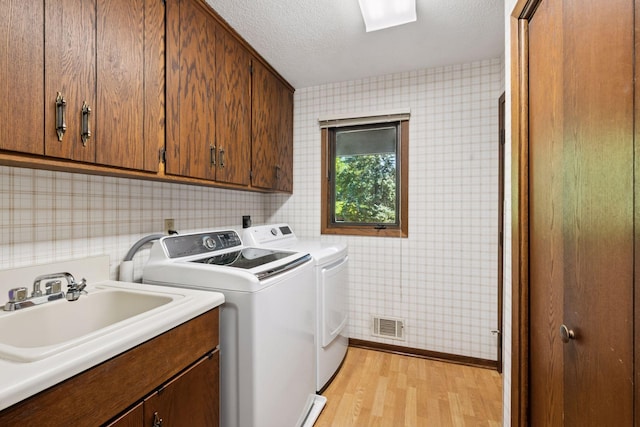 6205 Saint Albans Cir, Edina, MN 55439 - laundry room featuring cabinet space, independent washer and dryer, light wood-style floors, wallpapered walls, and a textured ceiling