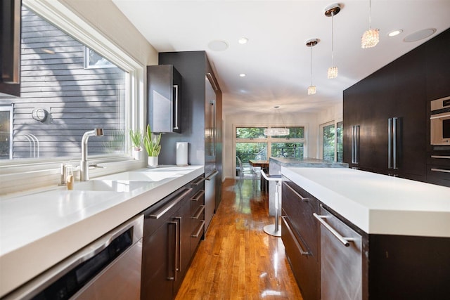 1921 Ewing Ave S, Minneapolis, MN 55416 - kitchen with appliances with stainless steel finishes, light wood-style flooring, light countertops, a kitchen island, and pendant lighting