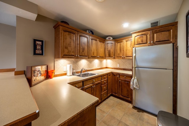 1100 27th St SW, Austin, MN 55912 - kitchen with freestanding refrigerator, backsplash, brown cabinetry, a peninsula, and recessed lighting
