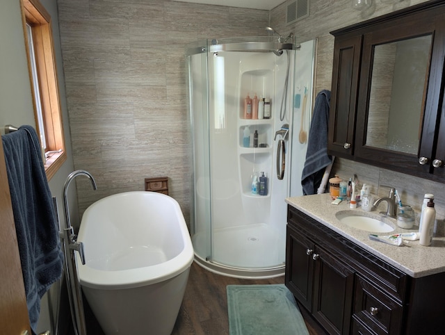 19963 County 18, Henrietta Twp, MN 56470 - bathroom with a stall shower, vanity, a freestanding bath, tasteful backsplash, and wood finished floors