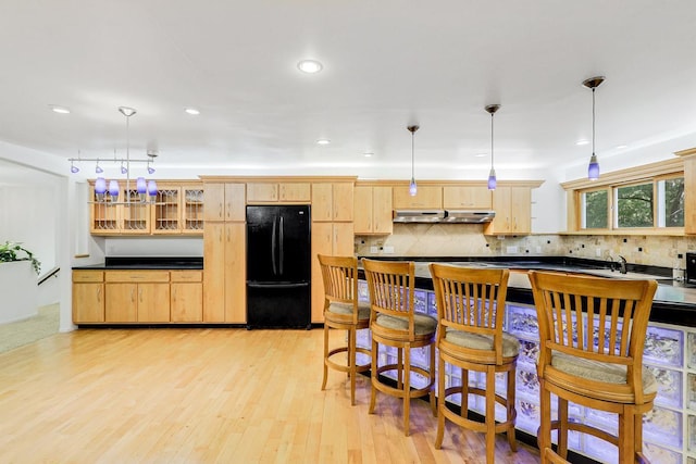 801 Corens Dr, Minnetonka, MN 55305 - kitchen with freestanding refrigerator, light brown cabinetry, dark countertops, under cabinet range hood, and light wood-type flooring