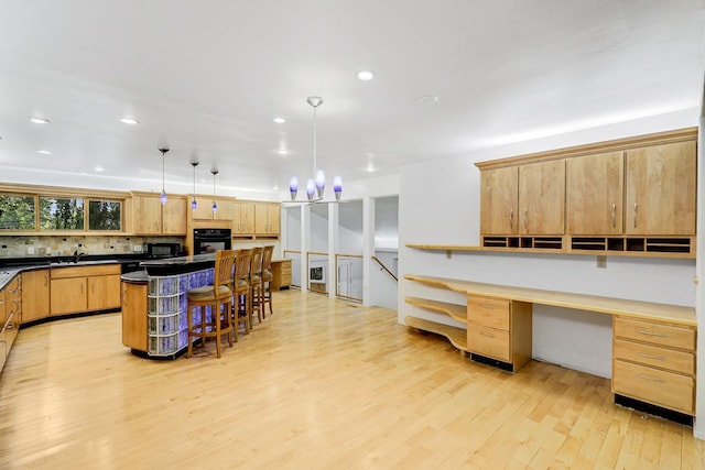801 Corens Dr, Minnetonka, MN 55305 - kitchen featuring black appliances, light wood-style flooring, built in desk, a kitchen bar, and dark countertops