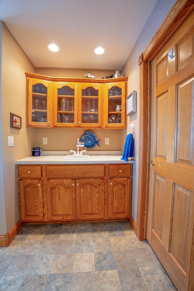 870 Andrew Dr NE, Lake Andrew Twp, MN 56273 - kitchen featuring glass insert cabinets, light countertops, brown cabinetry, and a textured ceiling